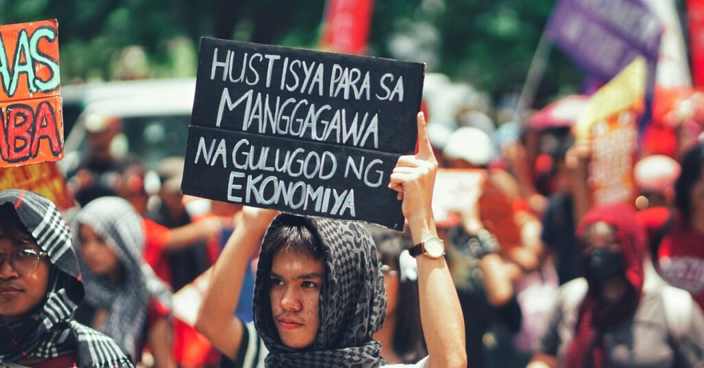 Protesters gathered outdoors holding signs demanding economic justice and workers' rights.