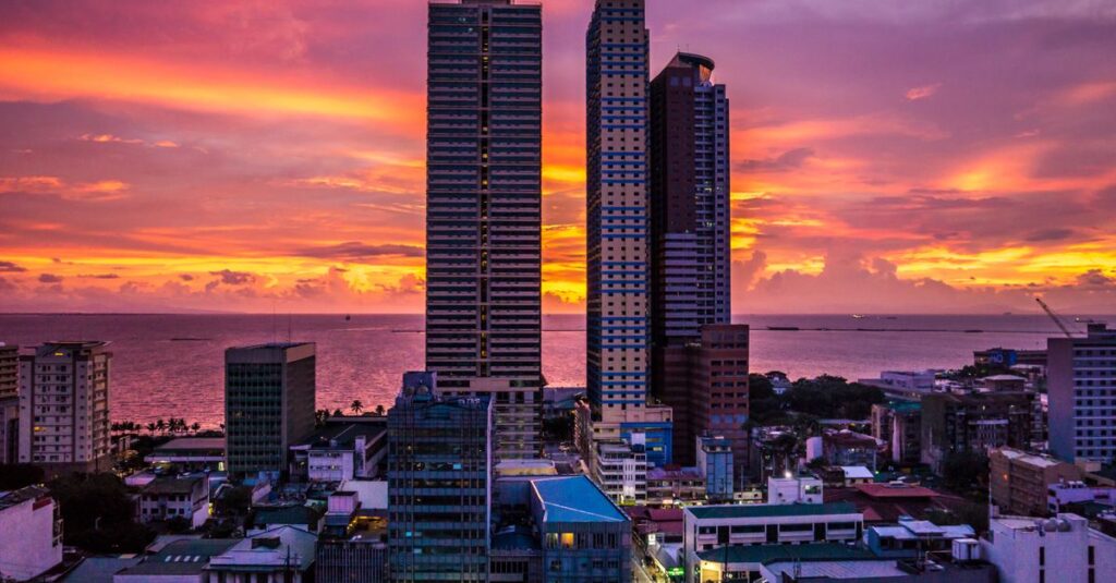 Stunning cityscape of Manila skyscrapers during a colorful sunset with sea view.