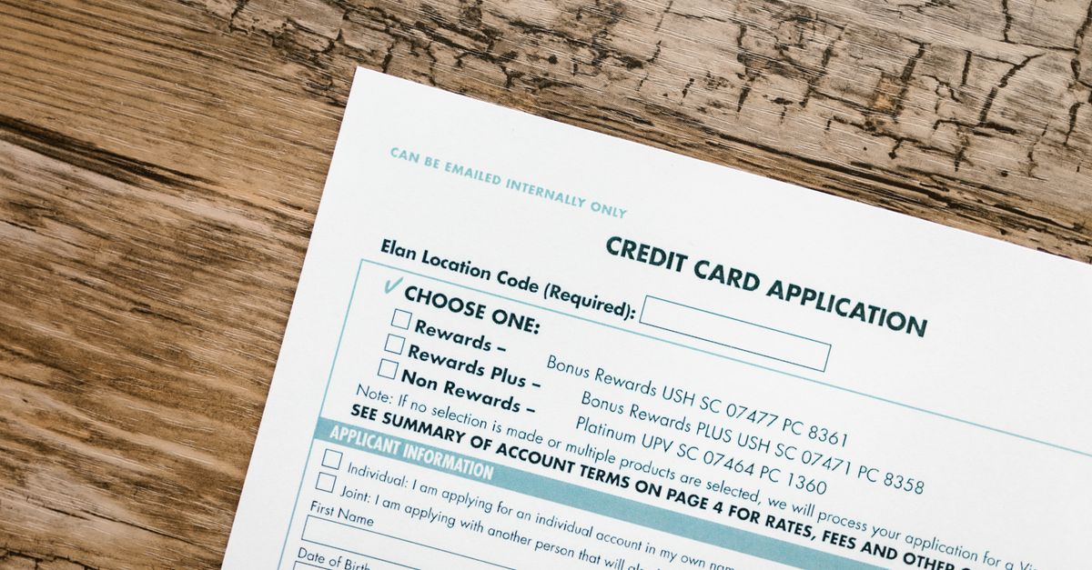 Top view of a credit card application form on rustic wooden background.