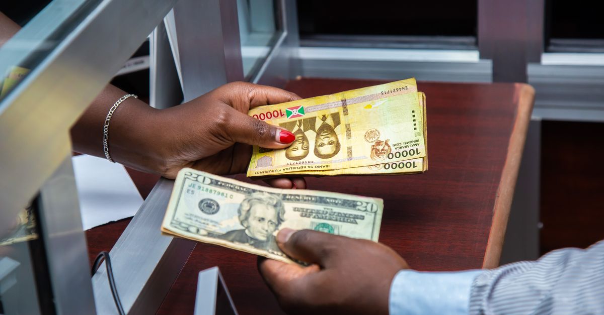 Burundian franc and US dollar exchange transaction at bank counter.