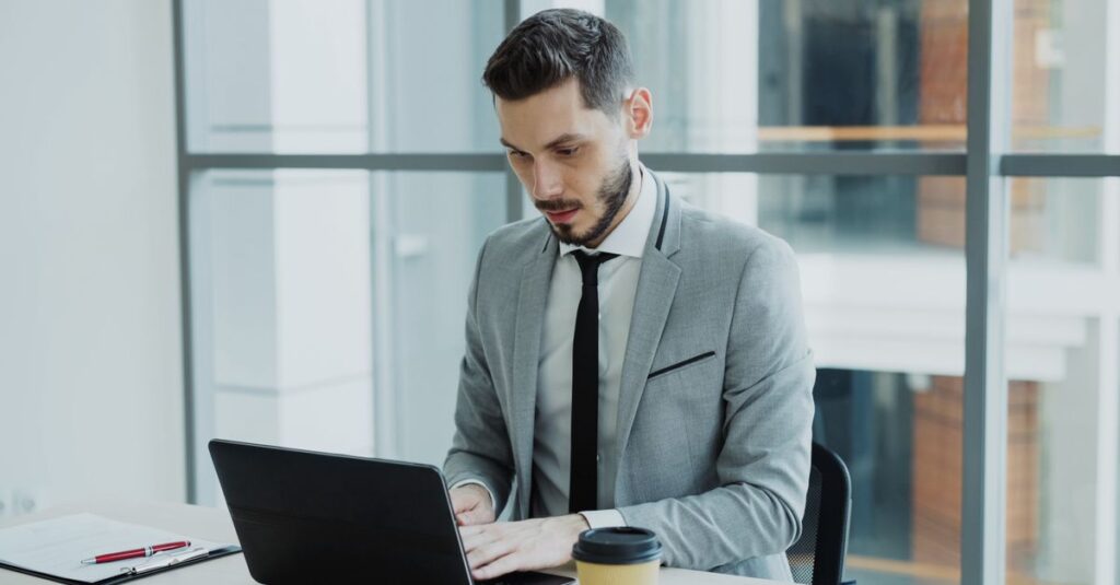 Businessman working on a laptop in a modern office setting.