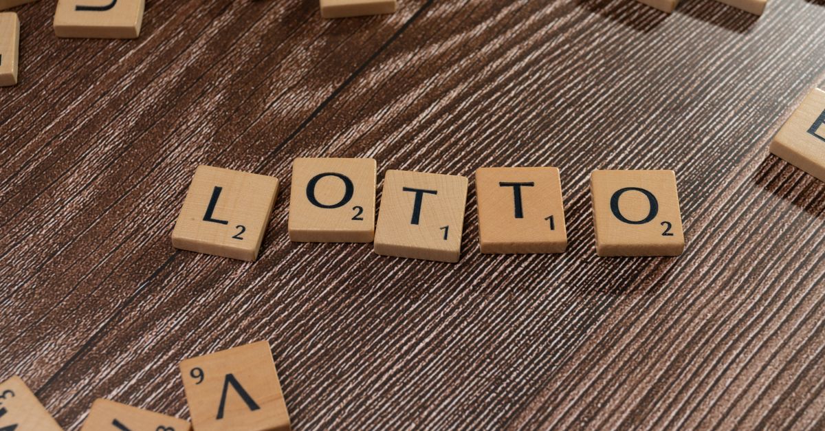 Scrabble tiles spelling 'LOTTO' on a wooden table surface, symbolizing chance and gaming.