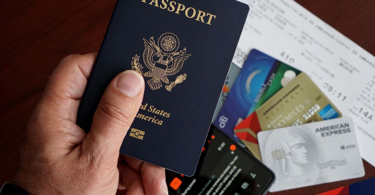 A close-up of a US passport with credit cards, tickets, and a mobile phone on a table.