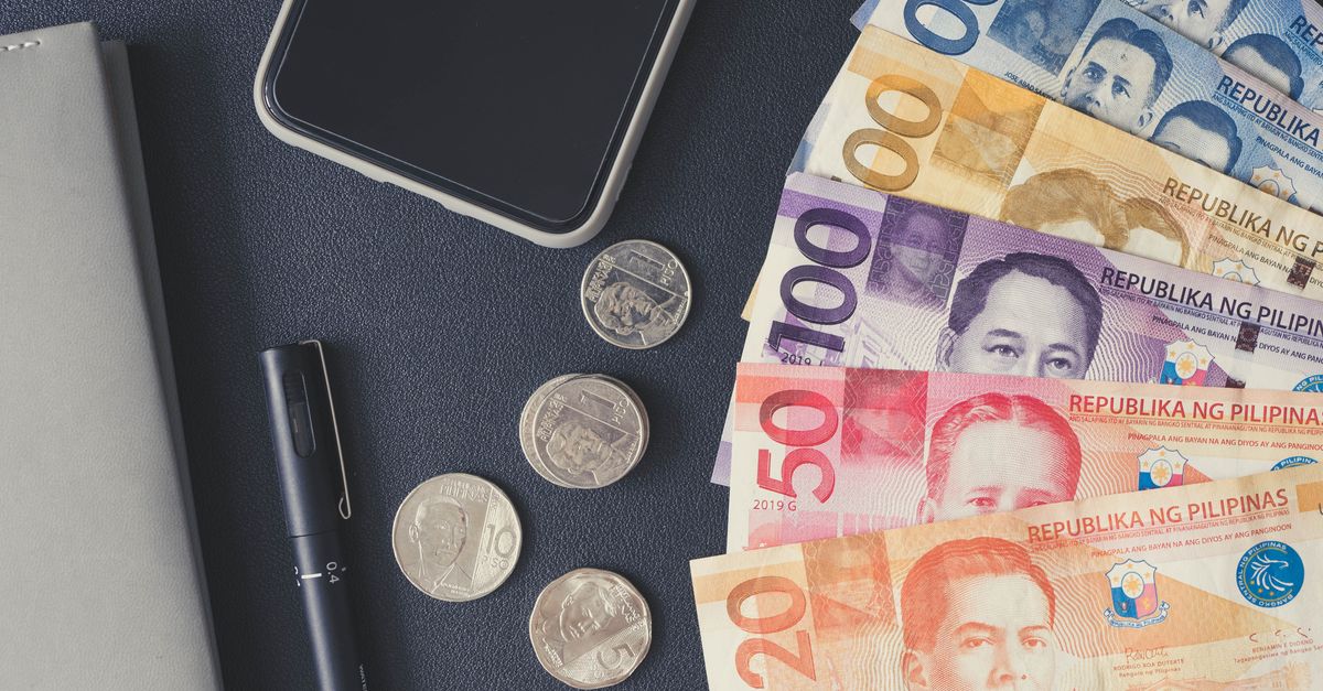 Flat lay of Philippine peso bills, coins, smartphone, and notebook. Ideal for financial themes.