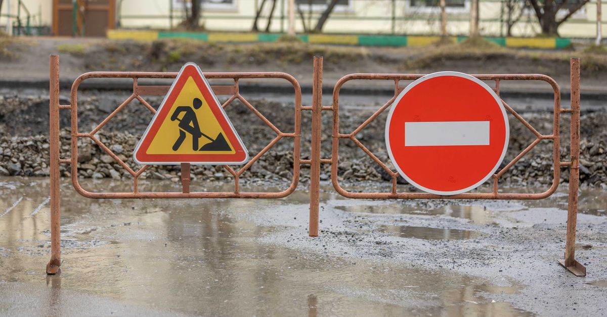 Close-up of construction signs and barriers in a muddy area outdoors, indicating no entry.