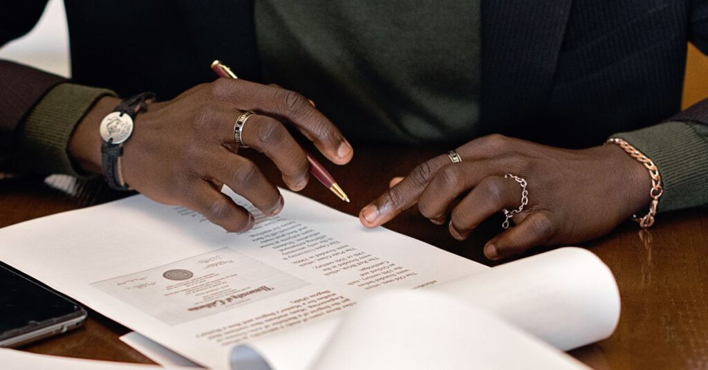 A business professional's hands signing a document at a desk, focusing on details.